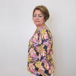 Woman wearing a floral blouse against a white wall