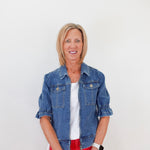Woman wearing a blue denim jacket and red pants against a white background
