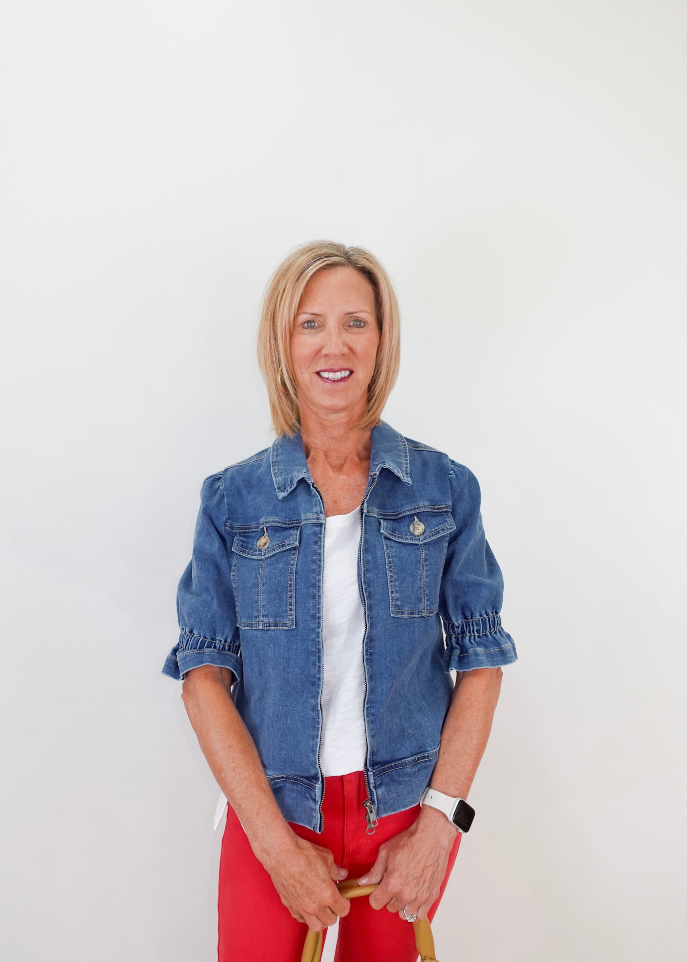 Woman wearing a blue denim jacket and red pants against a white background