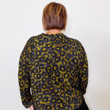 Person wearing a green and black leopard print top against a white background