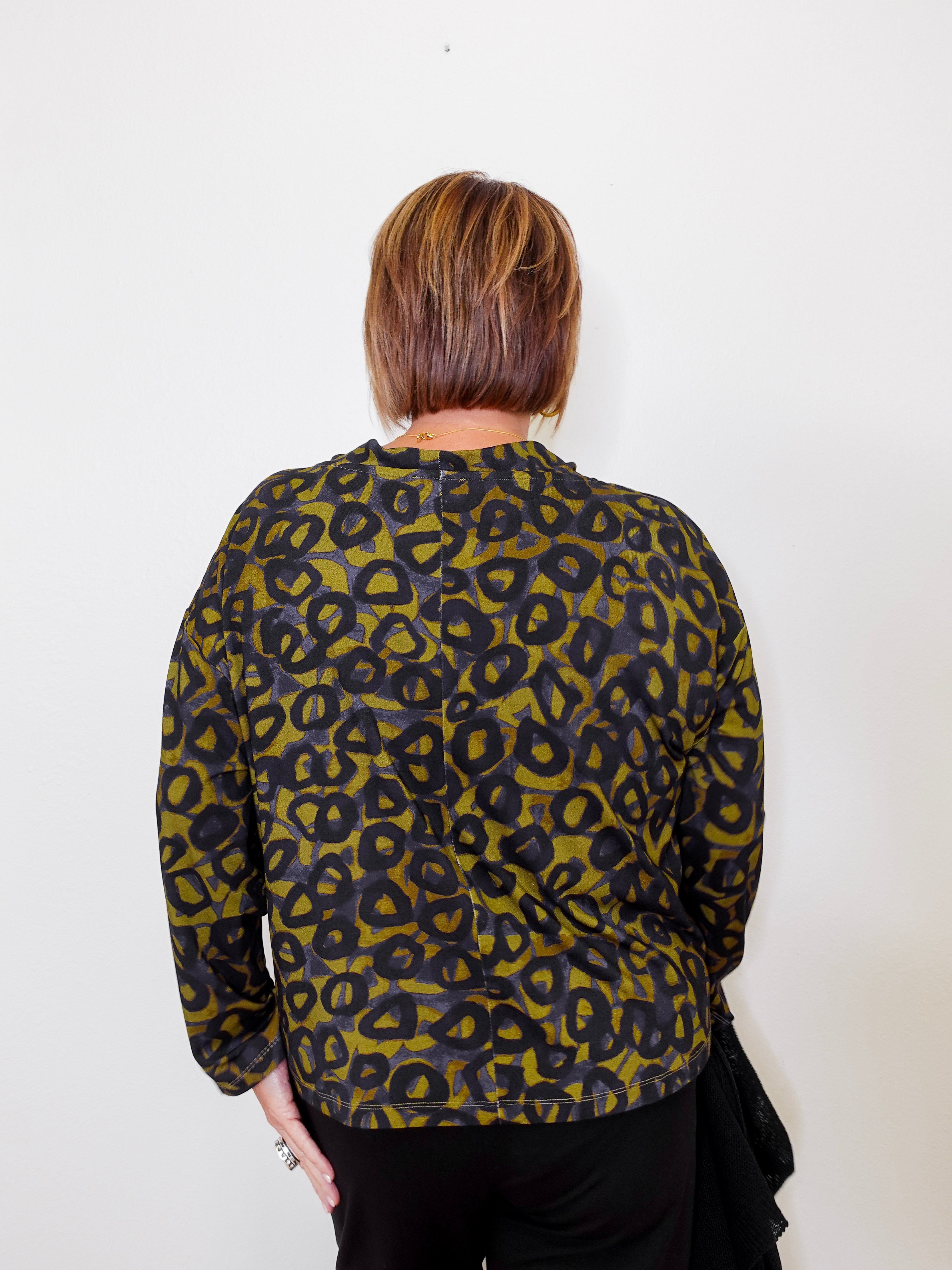 Person wearing a green and black leopard print top against a white background