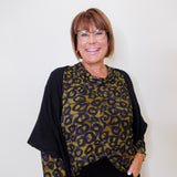 Woman wearing a leopard print top and black cardigan against a white background