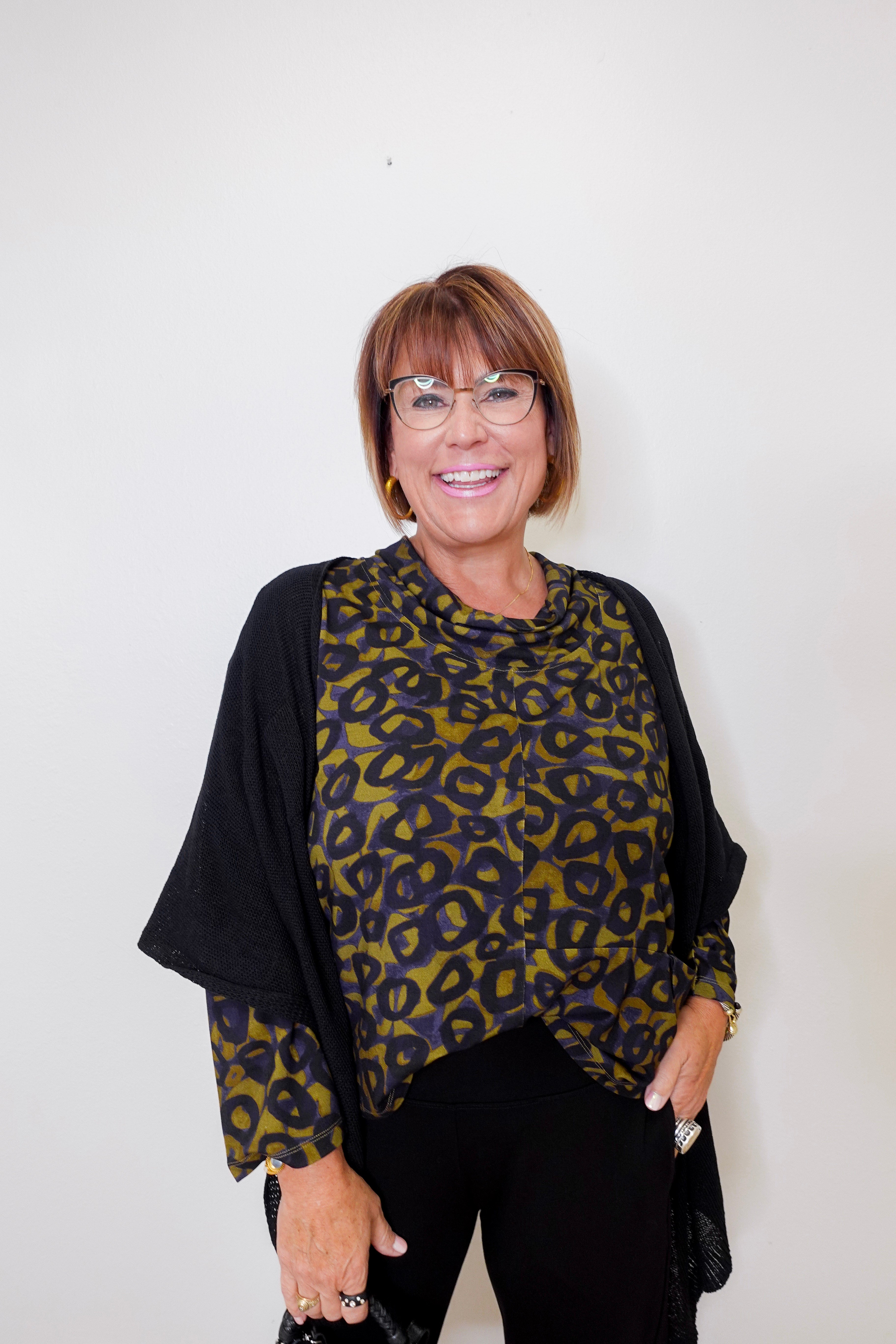 Woman wearing a leopard print top and black cardigan against a white background