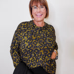 Woman wearing a leopard print top against a plain background