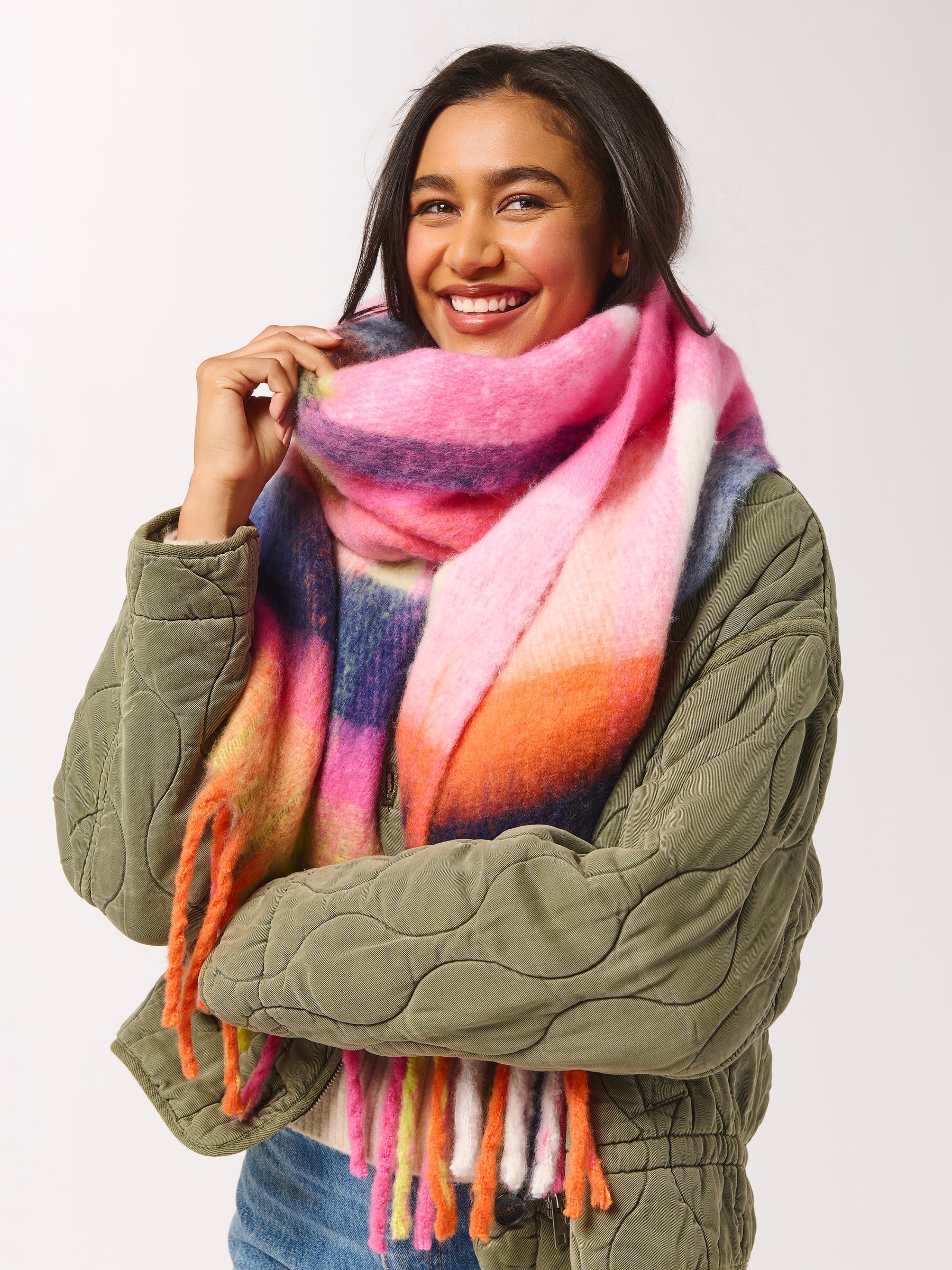 Woman wearing a colorful scarf and green jacket on a white background