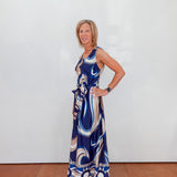 Woman wearing a blue patterned dress against a white wall.