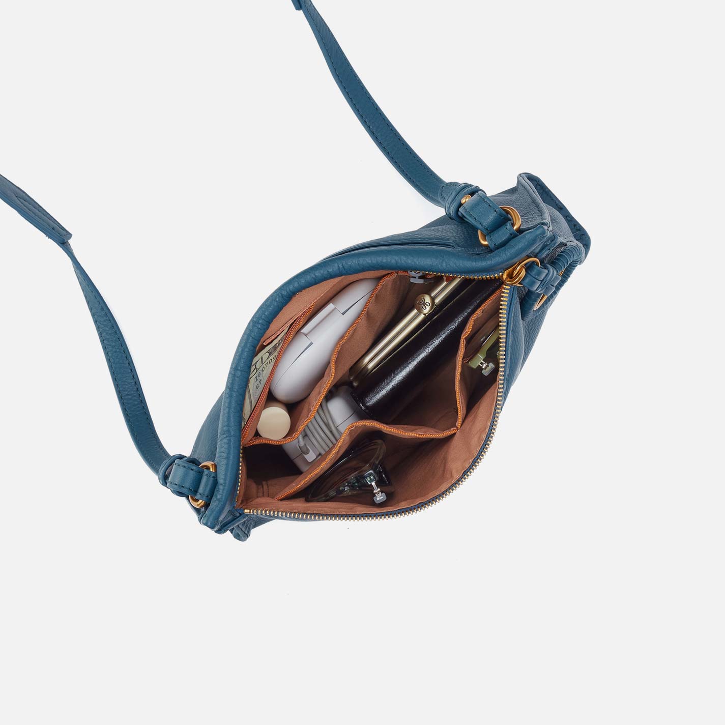 Blue crossbody bag with items inside on a light gray background