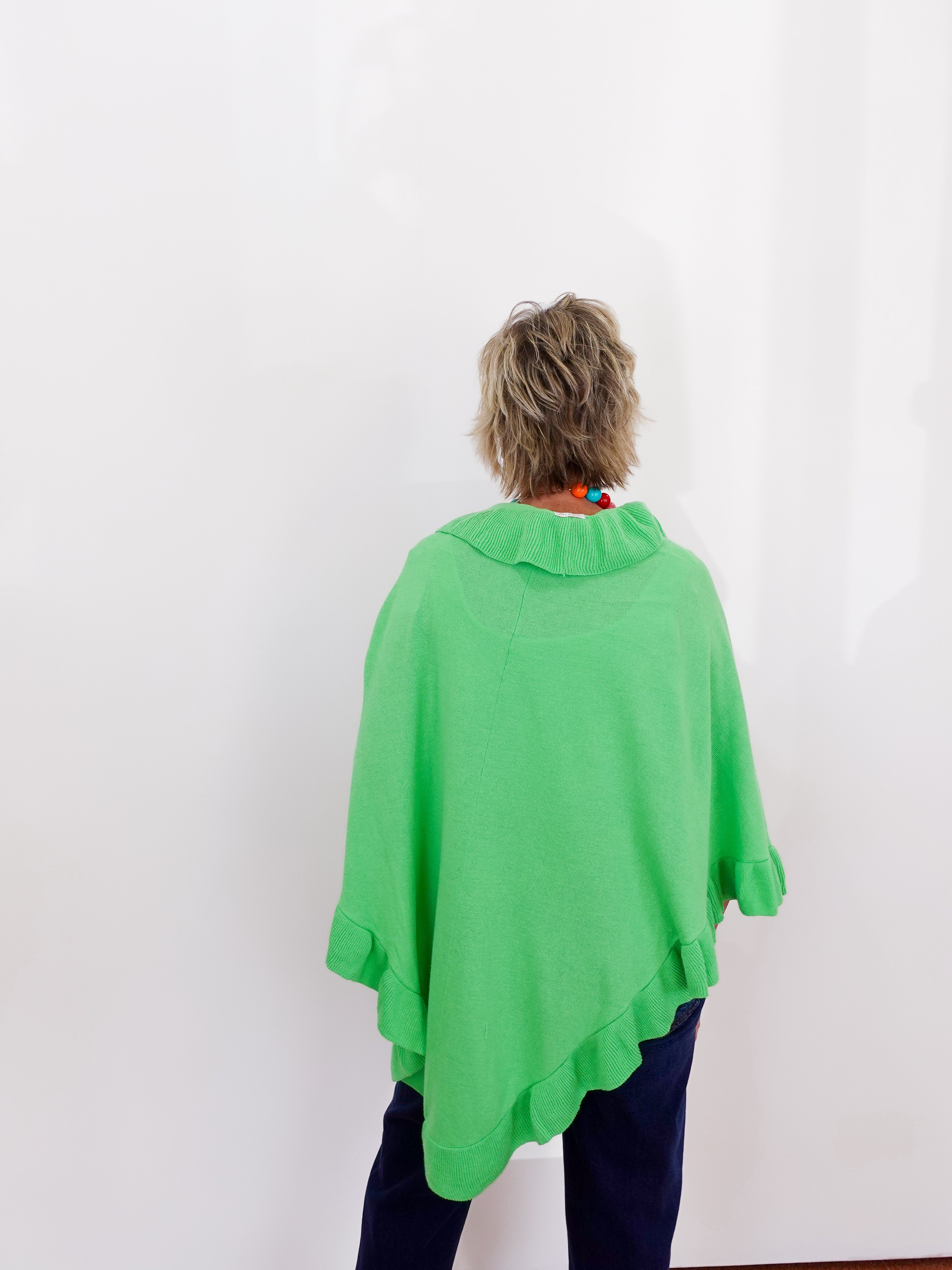 Person wearing a green poncho against a white background