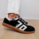 Black Adidas sneaker with white accents on a wooden floor