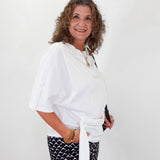 Woman wearing a white top and black patterned pants against a white background