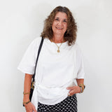 Woman wearing a white top and patterned pants against a plain background