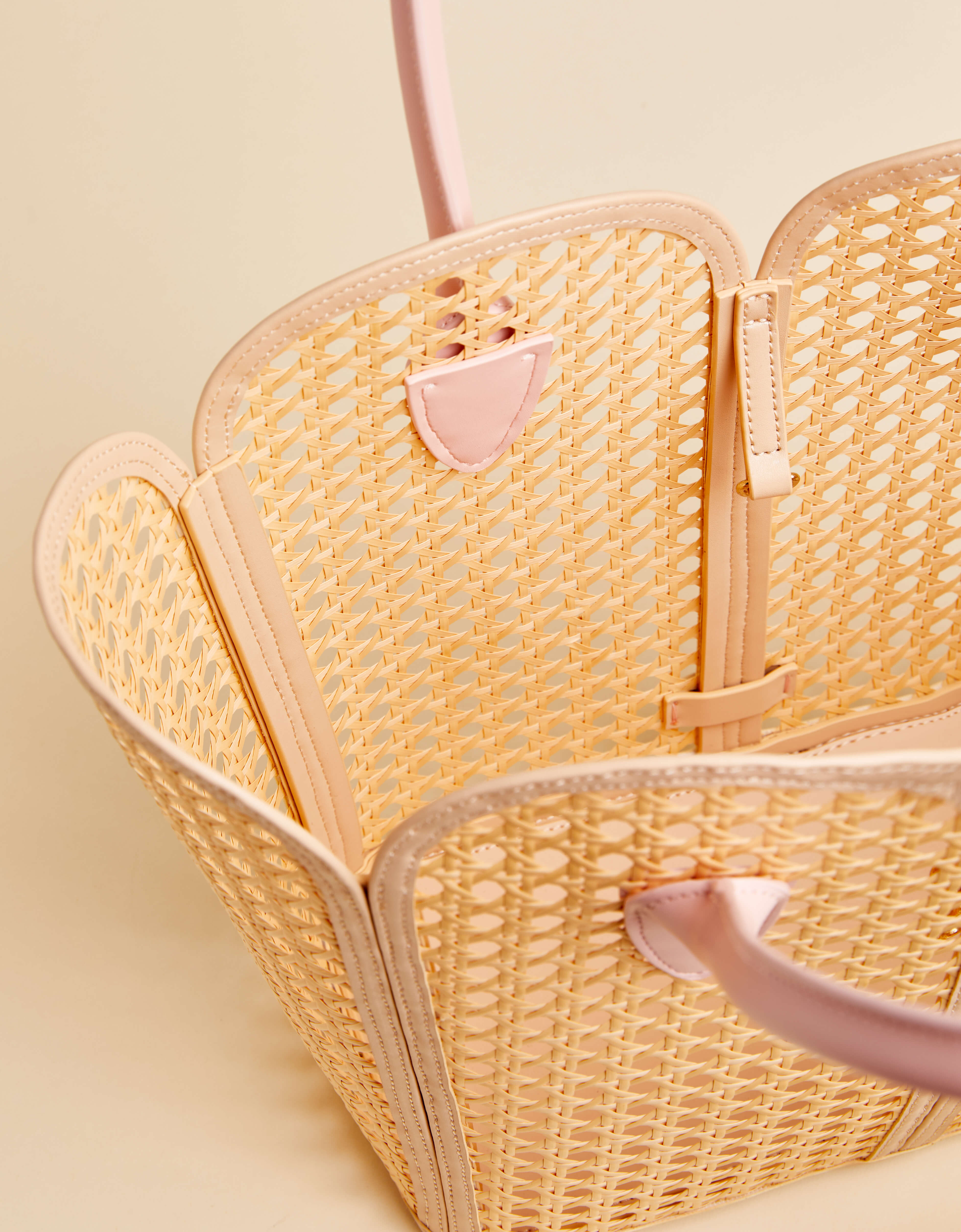 Woven handbag with pink accents on a light beige background
