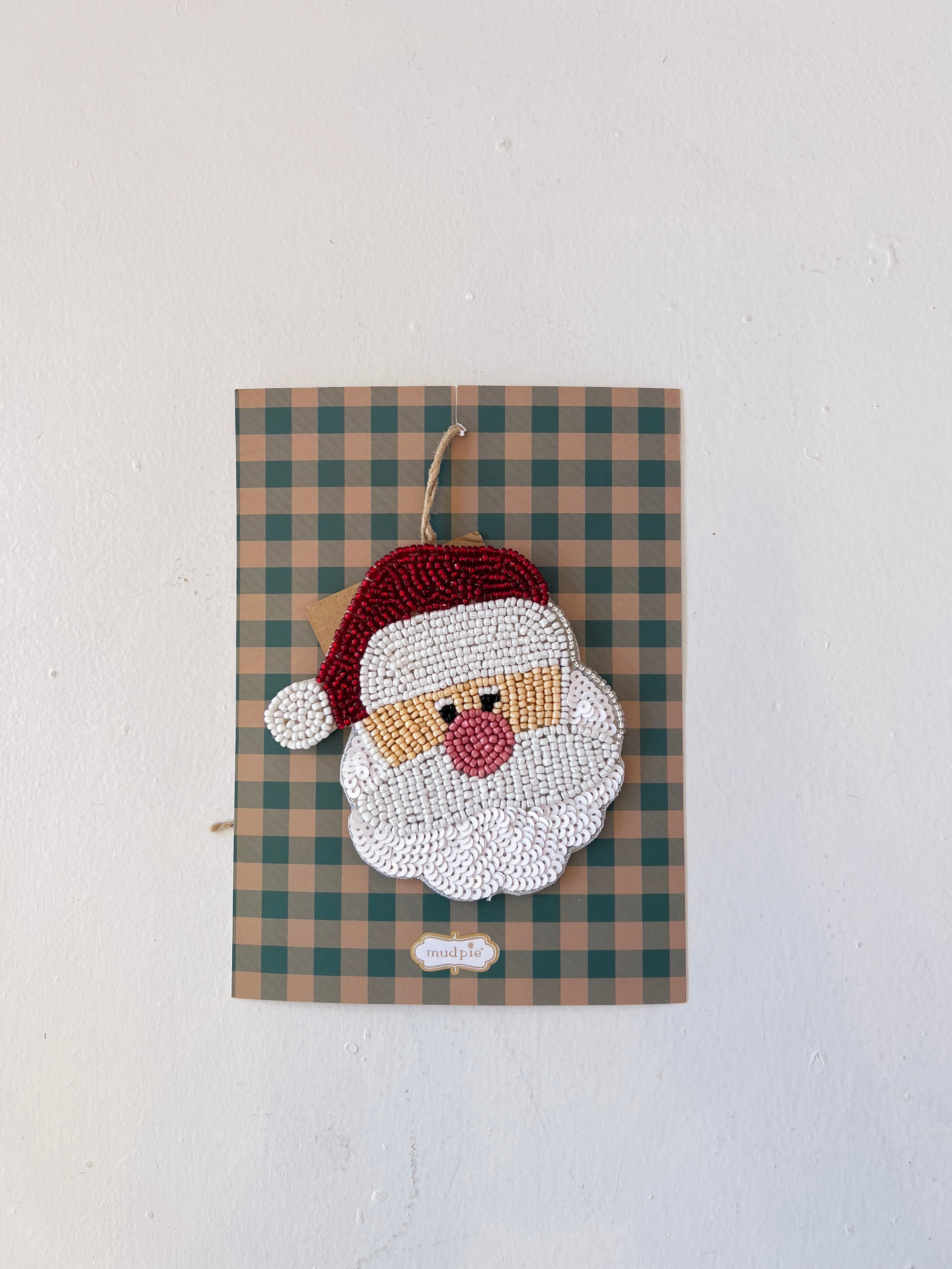 Decorative wall hanging with a beaded Santa Claus face on a plaid background