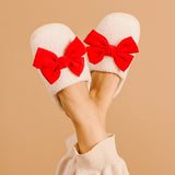 White slippers with red bows worn by a person on a beige background