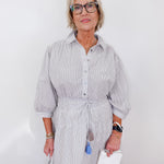 Woman wearing a light gray striped dress with a white background