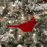 Red cardinal ornament on a snow-covered Christmas tree with blurred lights in the background