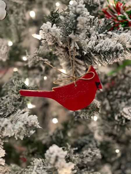 Red cardinal ornament on a snow-covered Christmas tree with blurred lights in the background