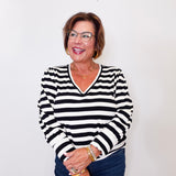 Woman wearing a black and white Karen Kane striped top against a plain background