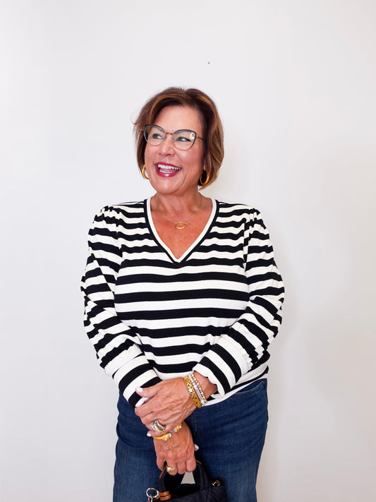 Woman wearing a black and white Karen Kane striped top against a plain background