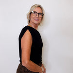 Woman wearing a black top and leopard print pants against a white background