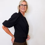 Woman wearing a black top and leopard print pants against a white background