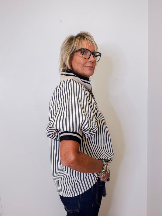 Person wearing a black and white striped shirt against a plain background
