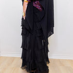Black ruffled dress with purple sequin sleeves against a white background