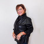 Woman wearing a black leather jacket against a white wall