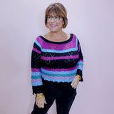 Woman wearing a colorful striped sweater against a plain background