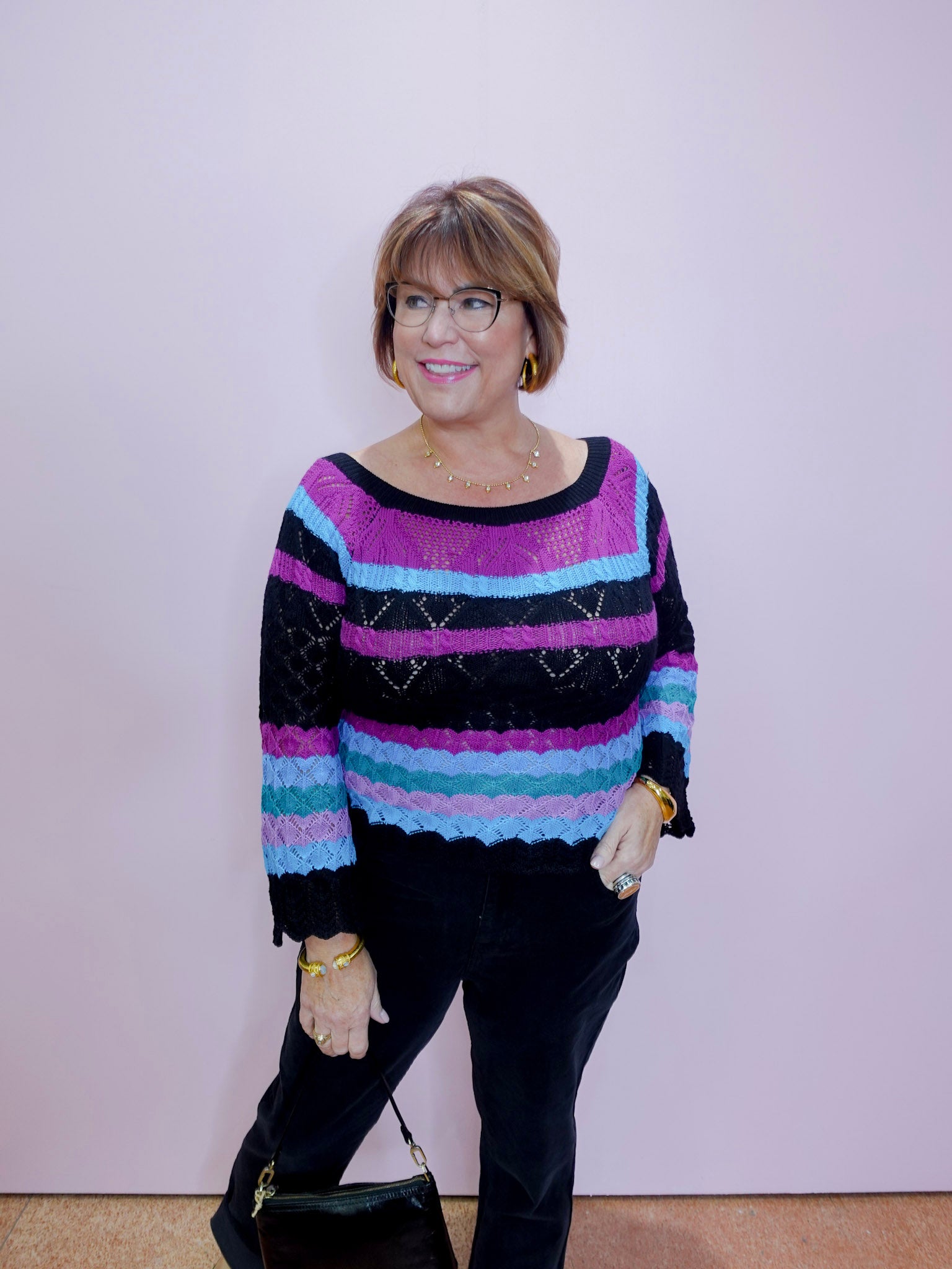 Woman wearing a colorful striped sweater against a plain background