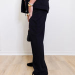 woman wearing a black pant against a white background. 