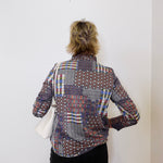 Person wearing a patterned shirt against a white wall
