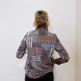 Person wearing a patterned shirt against a white wall