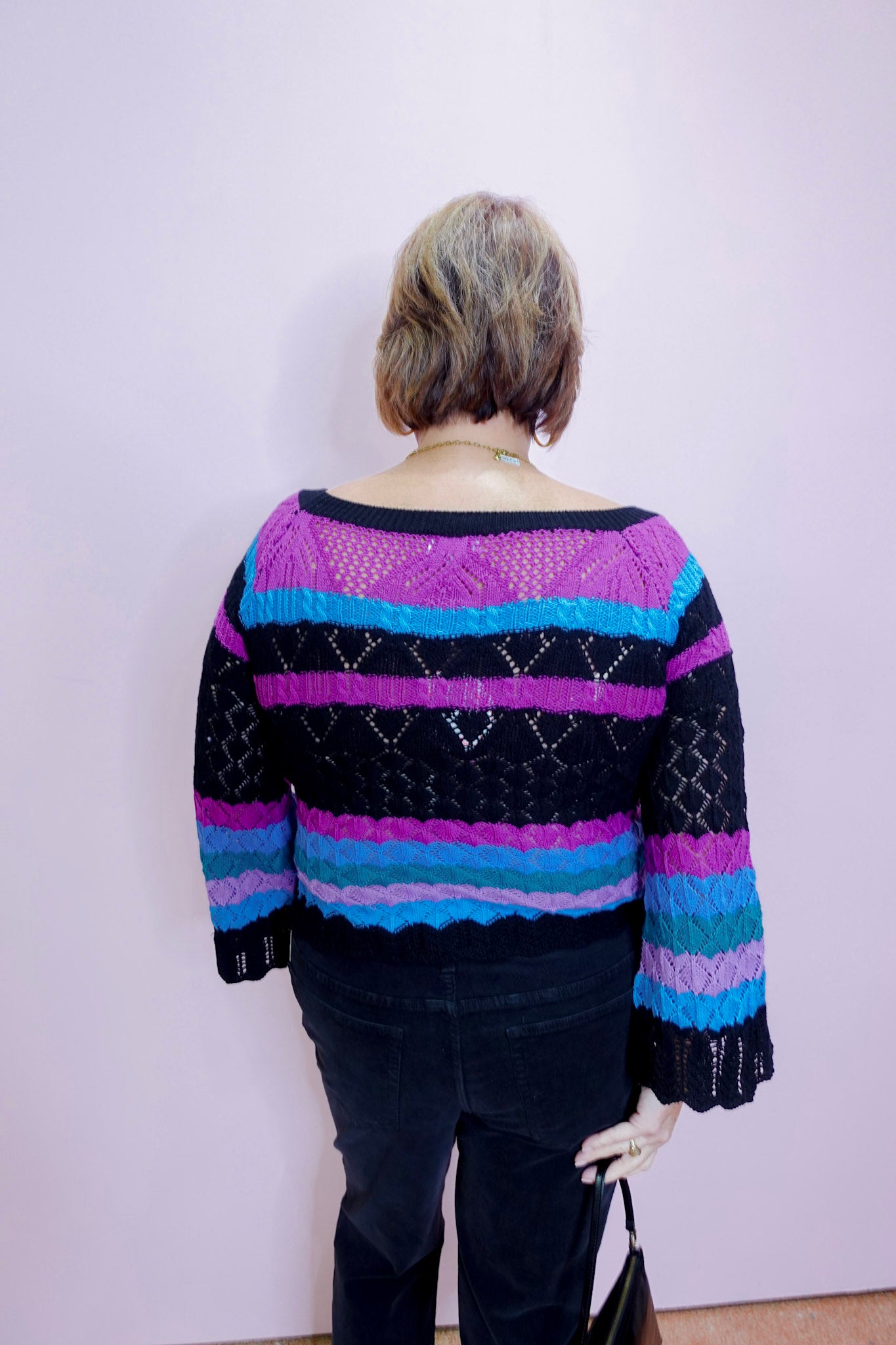 Person wearing a colorful striped sweater against a plain background