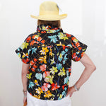 Person wearing a colorful floral shirt and yellow hat on a white background