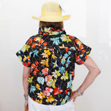 Person wearing a colorful floral shirt and yellow hat on a white background