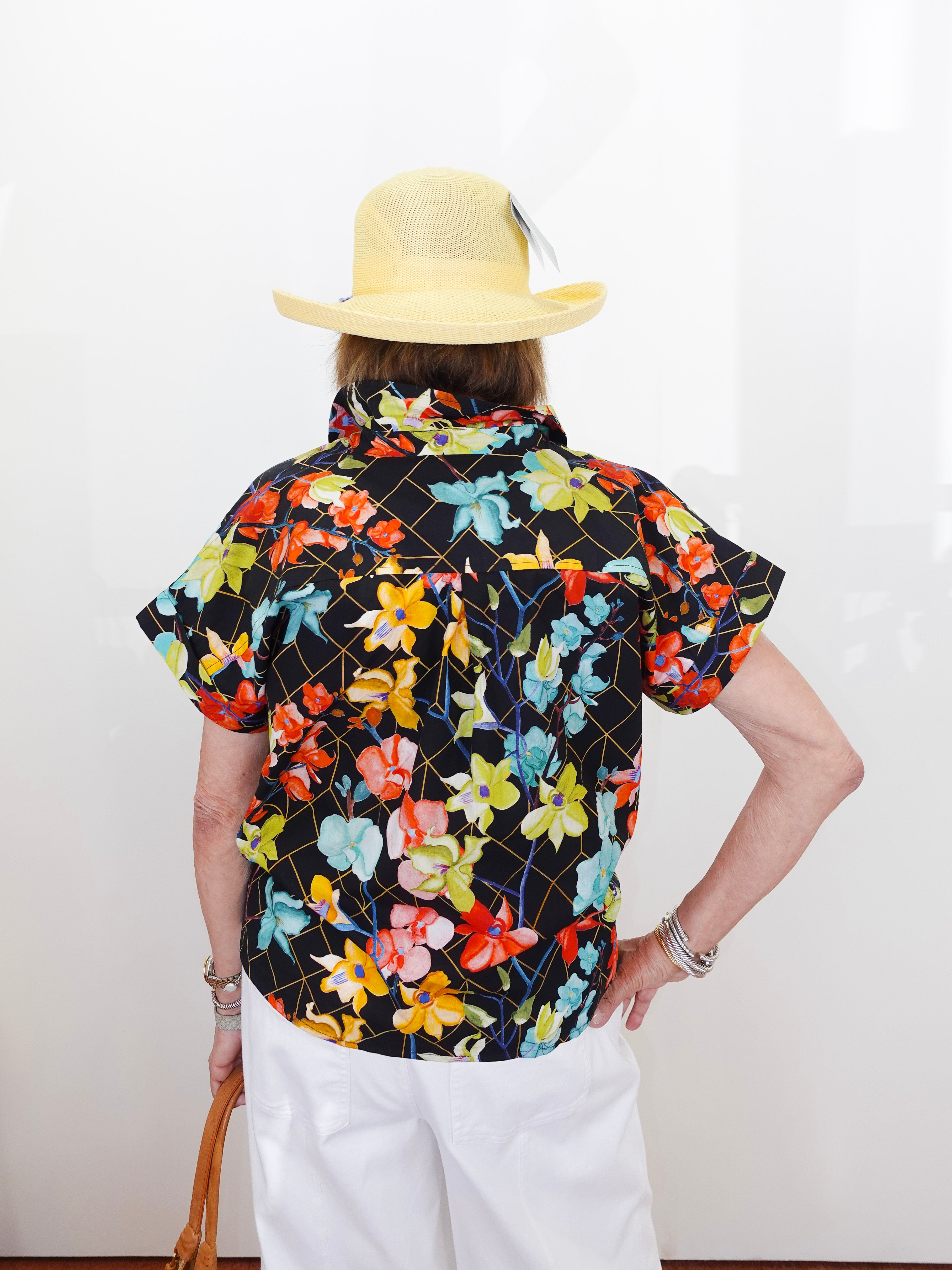 Person wearing a colorful floral shirt and yellow hat on a white background