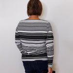 Person wearing a black and white striped sweater against a plain background