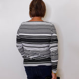 Person wearing a black and white striped sweater against a plain background