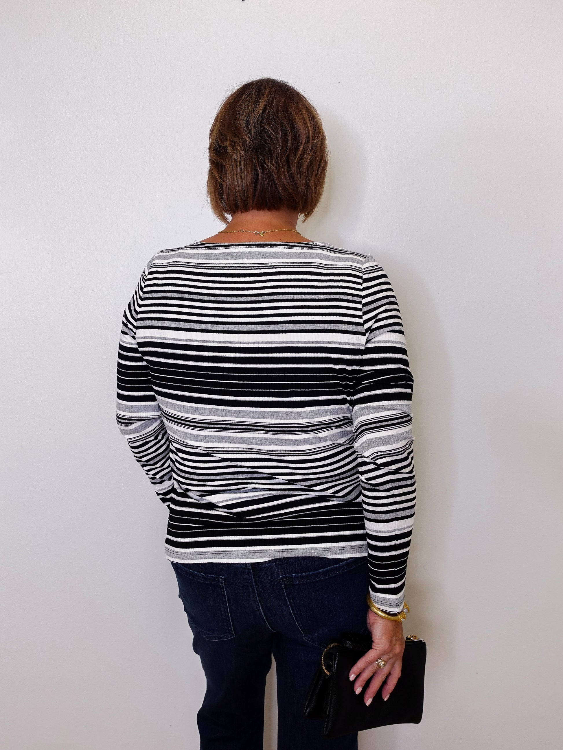 Person wearing a black and white striped sweater against a plain background