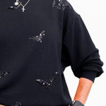 woman wearing a black sweatshirt that has black bats on it.