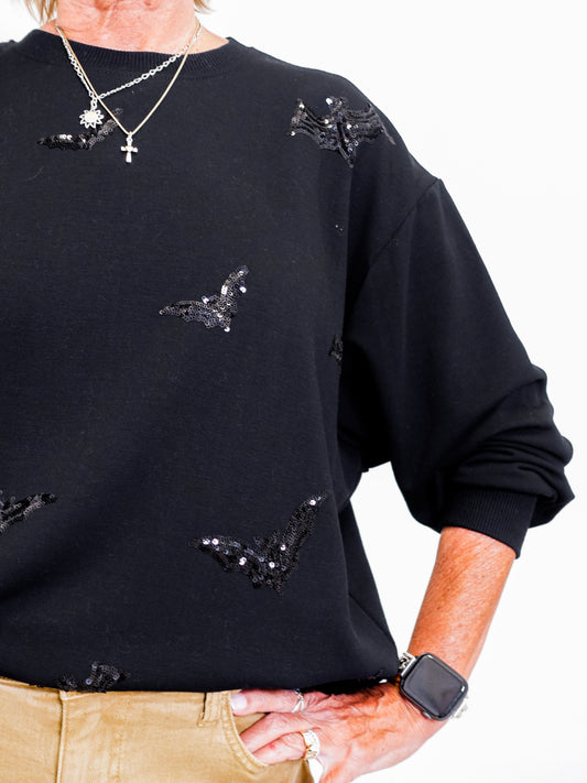 woman wearing a black sweatshirt that has black bats on it.
