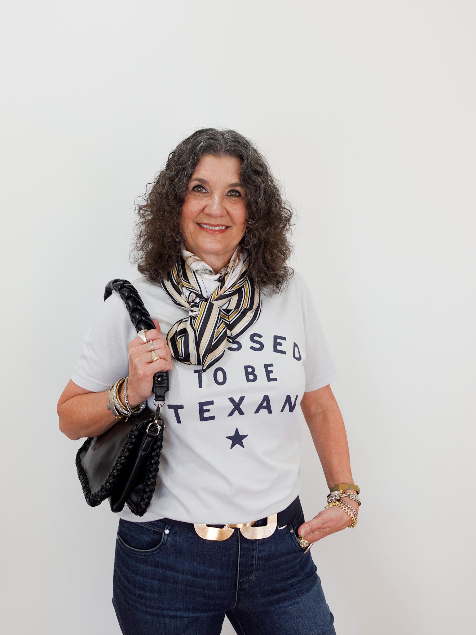 Woman wearing a 'Born to be Texan' t-shirt with a scarf and handbag against a white background