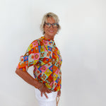 Woman wearing a colorful patterned blouse against a white background
