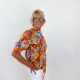 Woman wearing a colorful patterned blouse against a white background