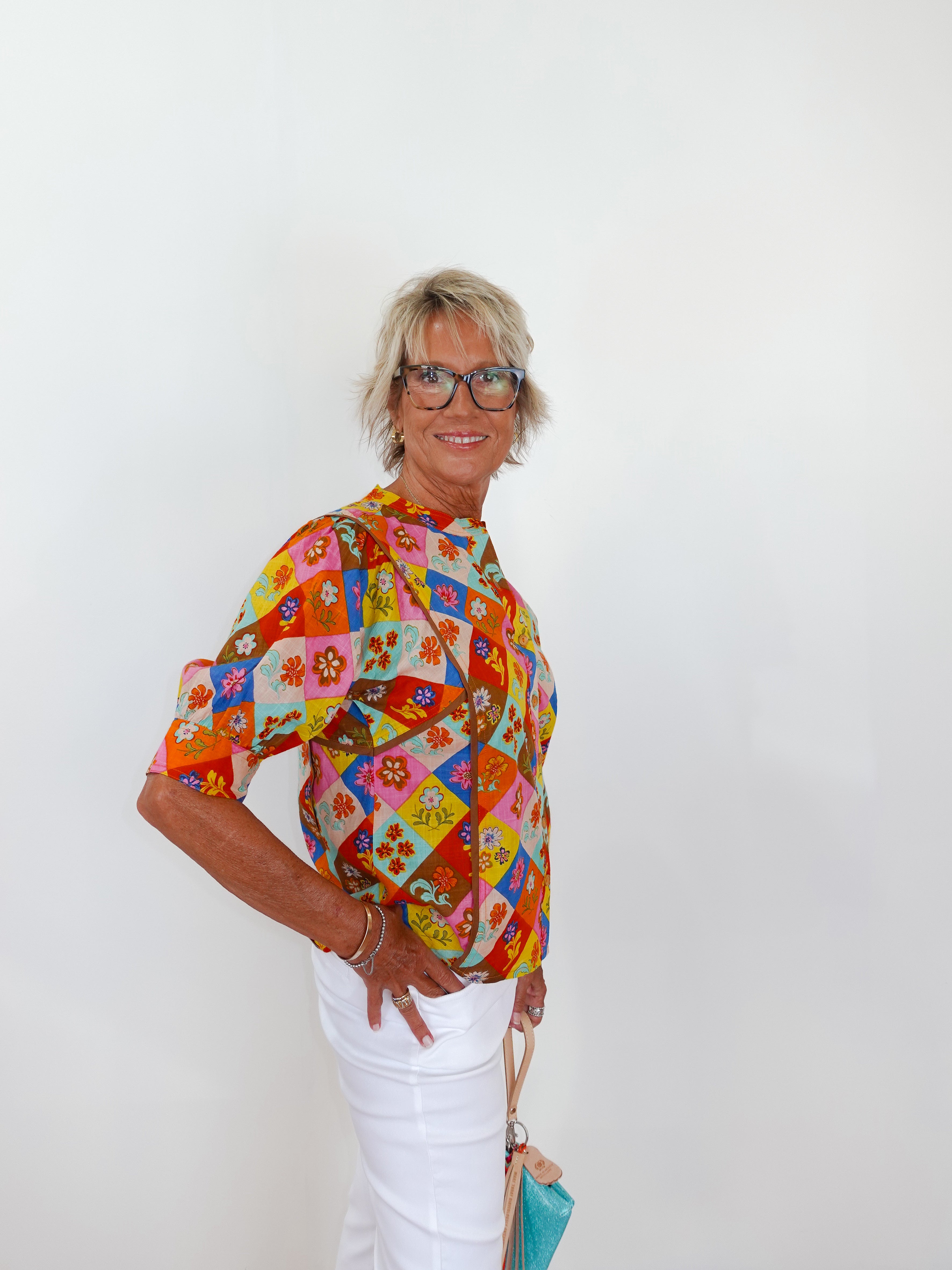 Woman wearing a colorful patterned blouse against a white background