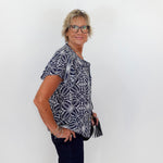Woman wearing a patterned shirt and glasses against a white background