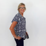 Woman wearing a patterned shirt and glasses against a white background