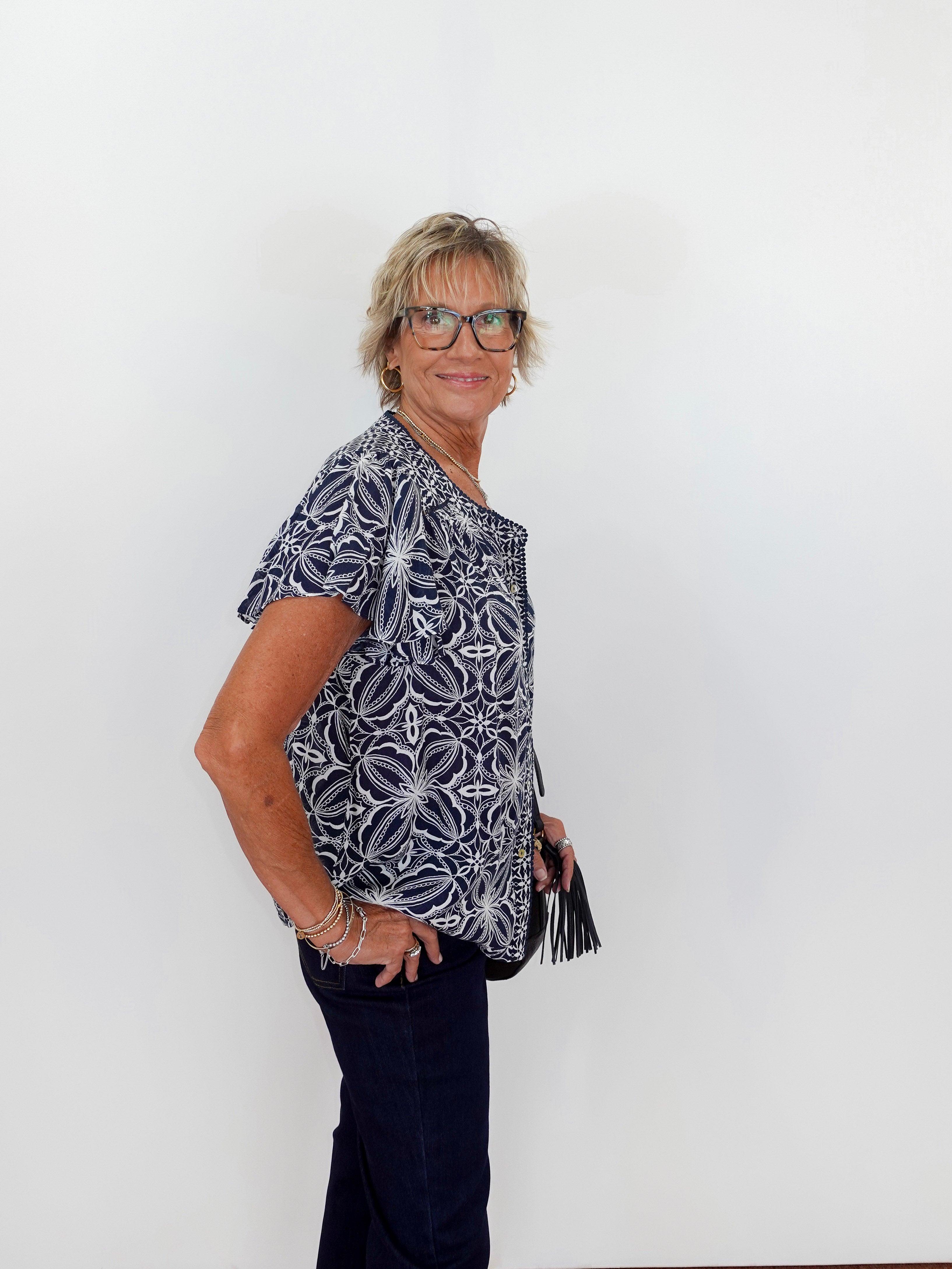 Woman wearing a patterned shirt and glasses against a white background