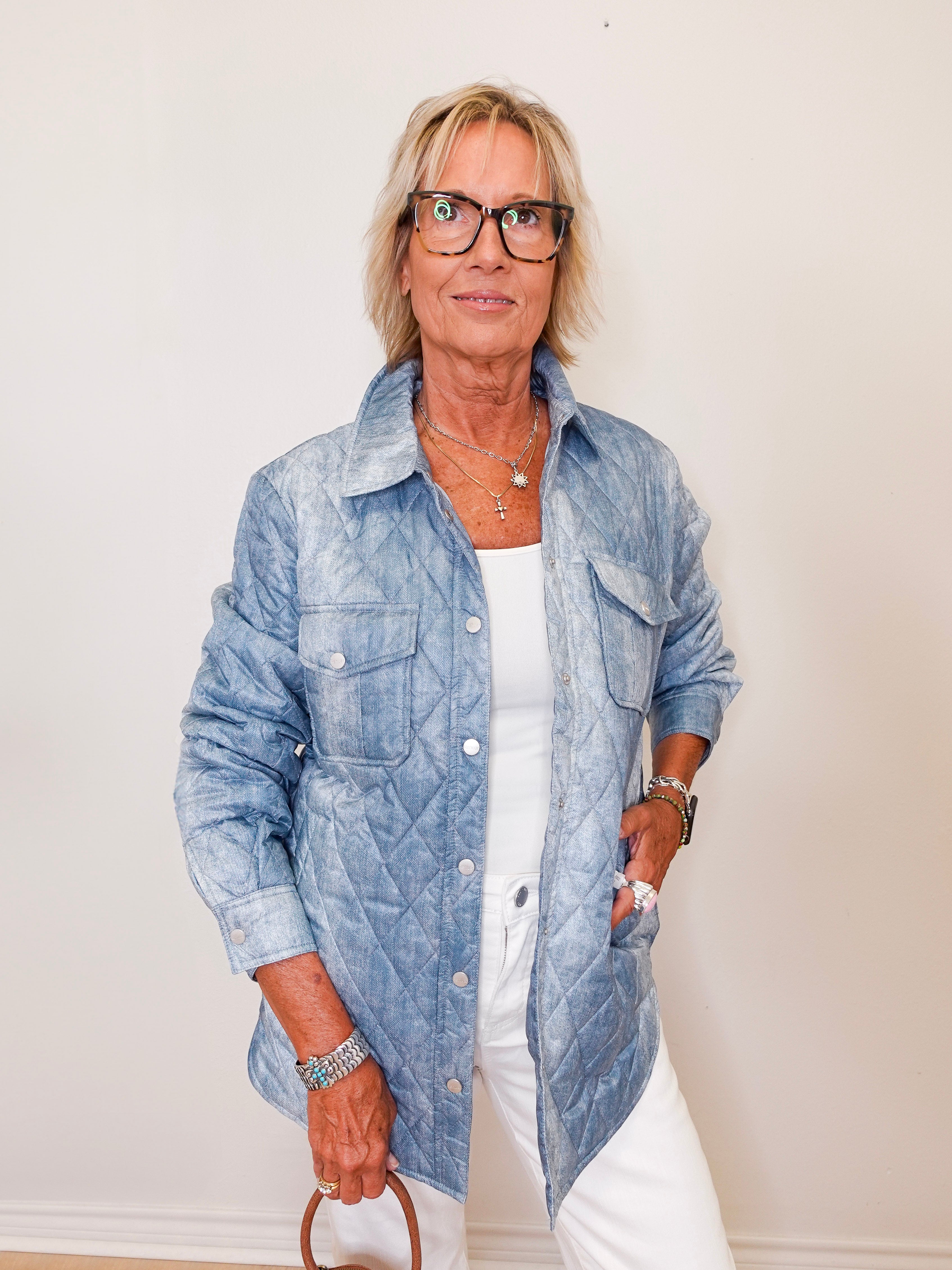 Woman wearing a blue denim jacket over a white shirt against a plain background